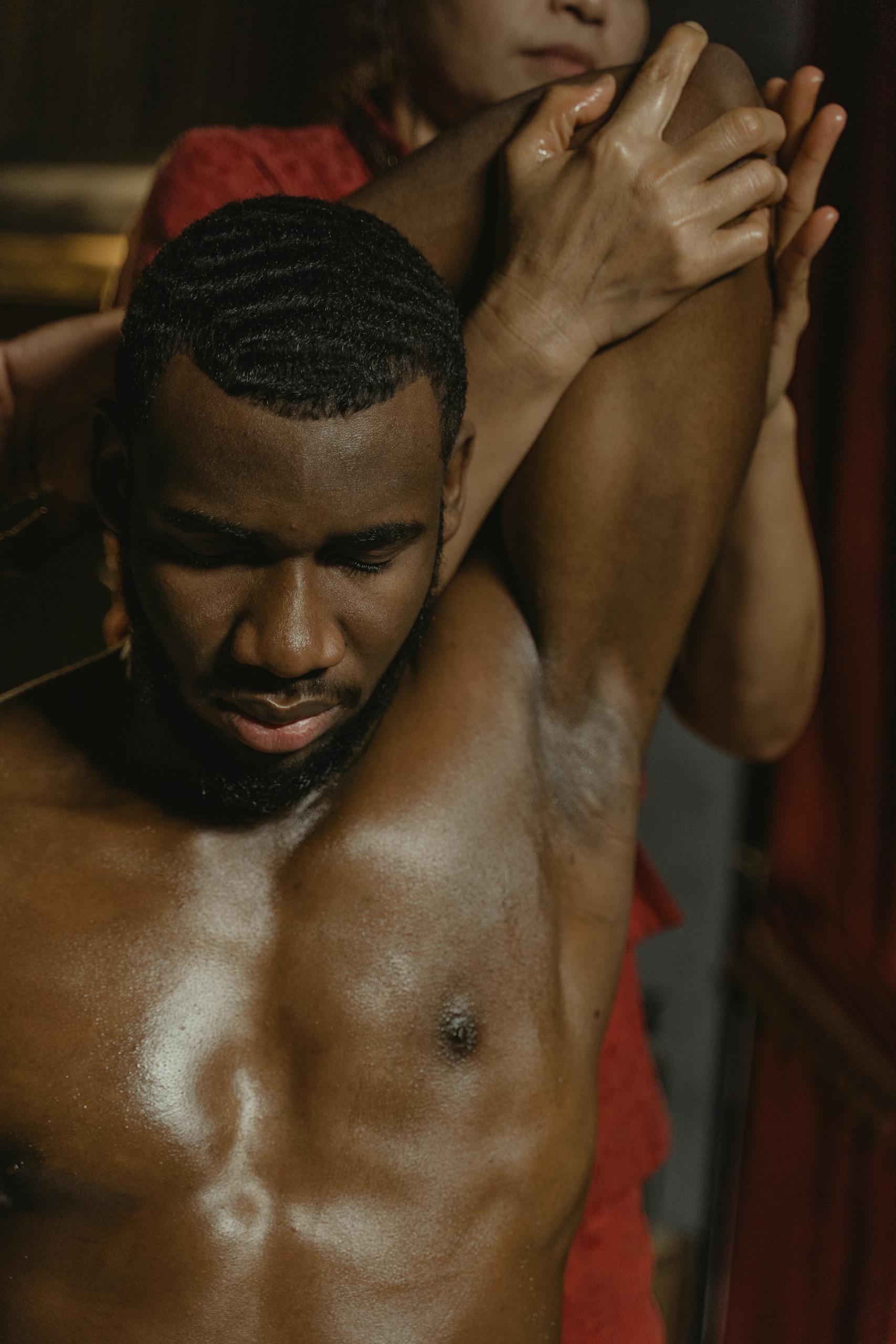 A relaxing massage therapy session with a shirtless African American man enjoying stress relief.